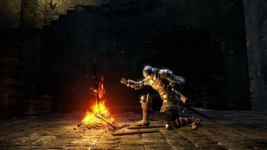En Dark Souls-karaktär knäböjer med en arm utsträckt över en brasa.